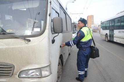 Сотрудники Госавтоинспекции совместно с ФМС провели рейд по выявлению незаконных маршрутных такси. На снимке: сотрудник ДПС и  маршрутное такси.