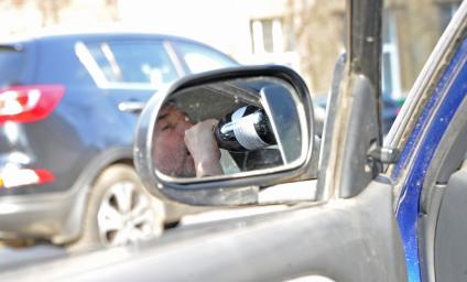 Пьянство за рулем. На снимке: водитель пьет вино в салоне автомобиля.