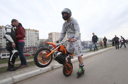 Парень в шлеме катается на роликовых коньках с мотоциклом.