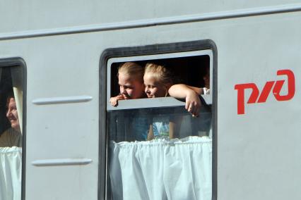 Дети выглядывают из окна железнодорожного вагона.