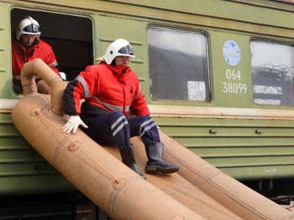 Комплексные учения МЧС на старом железнодорожном вокзале в Ульяновске. На снимке: спасатель спускается из окна поезда по надувному трапу.