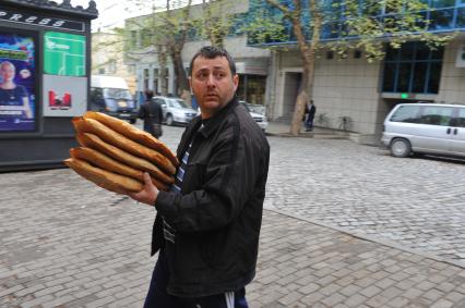 Мужчина несет в руках грузинский лаваш.