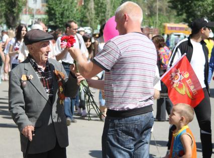 Мужчина с ребенком дарят ветерану гвоздики