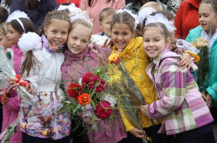 Четыре девочки держат в руках букеты цветов и обнимают друг друга