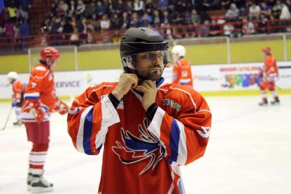 Фигурист Илья Авербух на хоккейном матче \"Под флагом добра\" поправляет свой шлем.