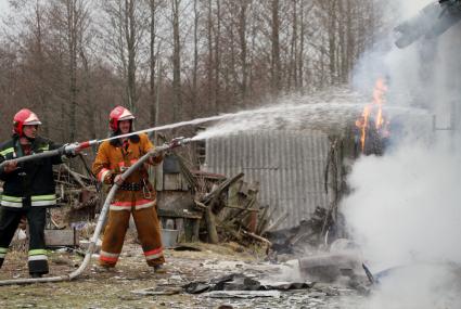 Пожарные тушат горящий дом