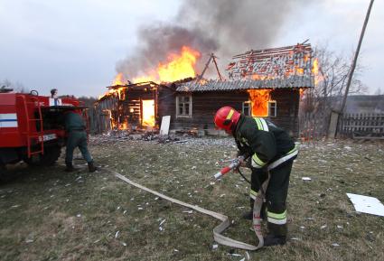 Пожарные тушат горящий дом
