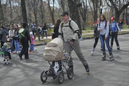 Парк `Сокольники`. На снимке: мужчина на роликовых коньках с детской коляской