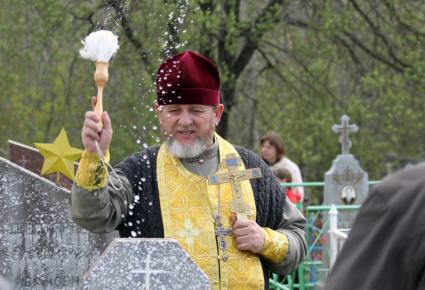 Священник Валентин Шелест освящает могилы на кладбище