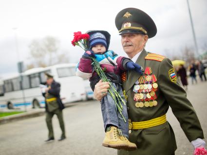 Празднование Дня Победы в Екатеринбурге. На снимке: ветеран несет на руках маленького ребенка.