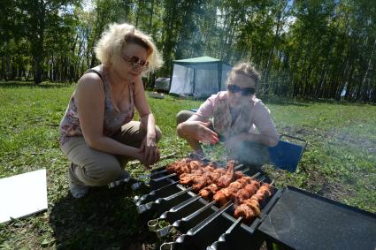 Отдых на природе. На снимке: приготовление свиного шашлыка.