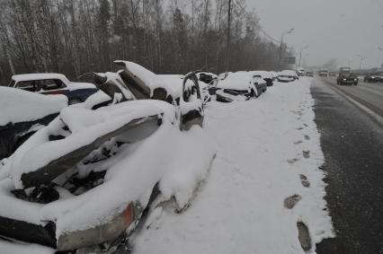 Заснеженные аварийные автомобили на обочине шоссе.