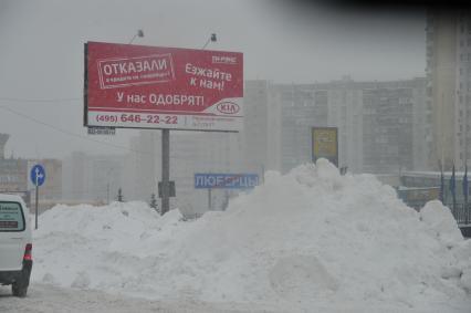 Последствия снегопада. На снимке: рекламный щит и сугробы.