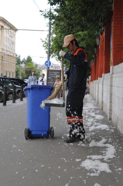 Тополиный пух в городе. На снимке: гастарбайтер убирает пух с улицы.