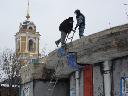 Мужчина спускается с крыши по лестнице