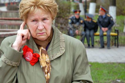 Митинг коммунистов в Туле. На снимке: пенсионер с значком партии `КПРФ` на фоне усаживающихся на лавочку полицейских.