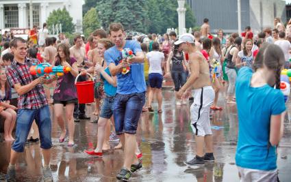 Массовое купание в фонтане на ВВЦ. Молодые люди обливают девушку водой стреляя из водных пистолетов.