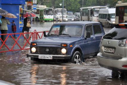Последствия ливня в городе - затопленные улицы. Автомобиль едет по затопленной улице.