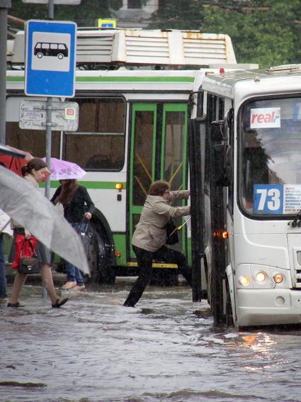 Последствия ливня в городе - затопленные улицы. Люди садятся в автобус.