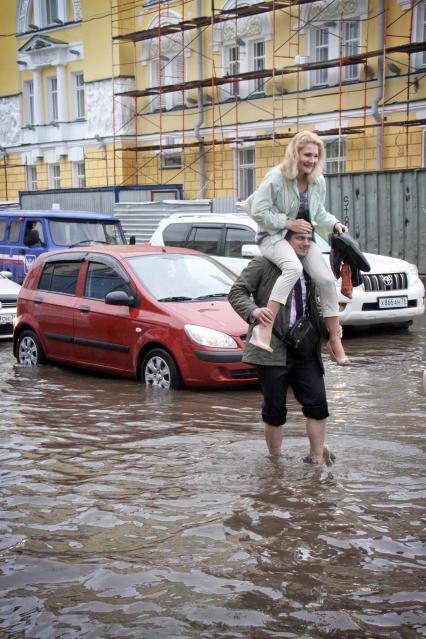 Последствия ливня в городе - затопленные улицы. Мужчина переходит босиком затопленную улицу, несет на плечах девушку.
