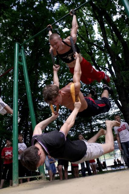Спортсмены выполняют силовой акробатический трюк на турнике