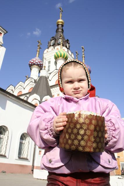 Ребенок с куличом в руках на фоне церкви.