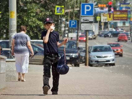 Ребенок на улице прикрывает нос от тополиного пуха.