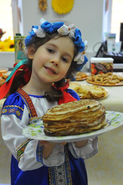 Участница коллектива `Непоседы`. На снимке: девочка держит тарелку с блинами.