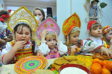 Участники коллектива `Непоседы`угощаются масленичными блинами.