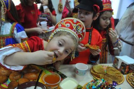 Участники коллектива `Непоседы`угощаются масленичными блинами.