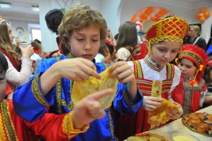 Участники коллектива `Непоседы`угощаются масленичными блинами.