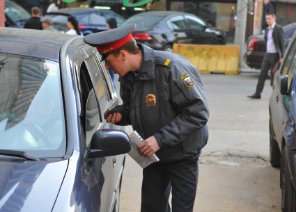 Инспектор полиции проверяет документы у водителя.