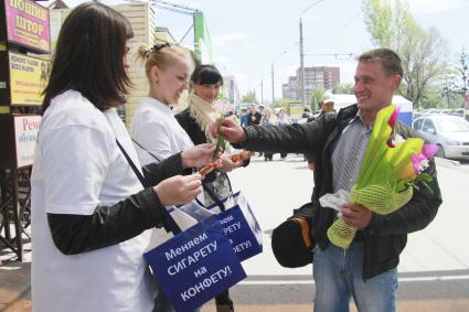 День отказа от курения. Акция `Поменяй сигарету на конфету`. Прохожий дарит девушкам цветы.