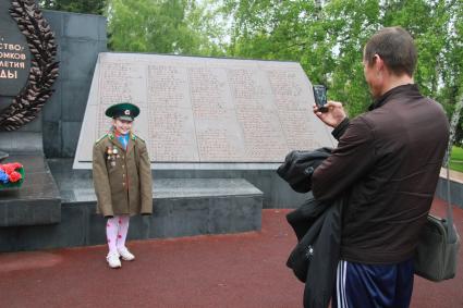 День пограничника. Девочка в военном кителе позирует у мемориала.