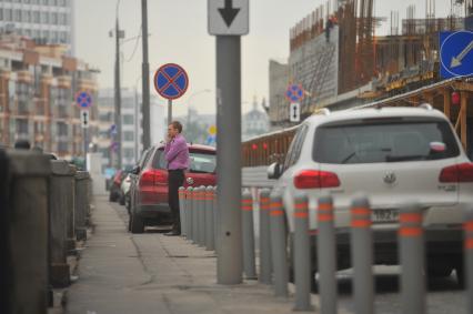 Припаркованный автомобили и знак `Остановка запрещена`.