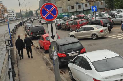 Припаркованный автомобили и знак `Остановка запрещена`.