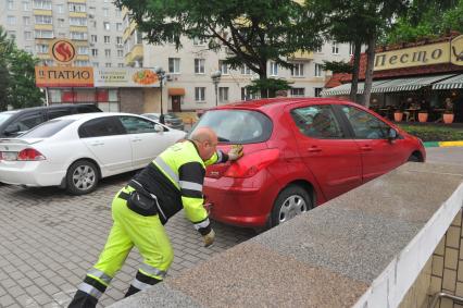 Припаркованный автомобили и сотрудник службы эвакуации `Дорожные Ангелы`.