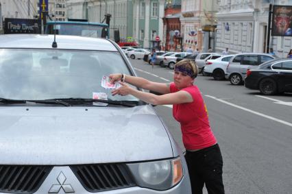 Девушка с рекламными листовками у автомобиля Mitsubishi.