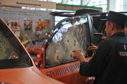 ВВЦ.  Международный салон по обеспечению безопасности `Комплексная безопасность-2013`.  Toyota Land Cruiser на стенде`Взрывостойкая защита`. На снимке: мужчина рассматривает специальное многослойное стекло автомобиля