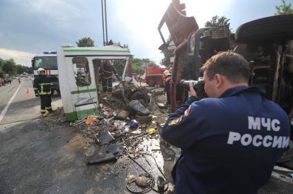 В результате ДТП под Подольском, погибли 18 пассажиров рейсового автобуса. Водитель КамАЗа не уступил дорогу автобусу и на полном ходу протаранил его. В результате удара груженного щебнем грузовика у автобуса оторвало заднюю часть. На снимке: сотрудники МЧС на месте аварии.