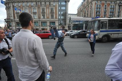 Несанкионированная акция в поддержку блогера, основателя антикоррупционного проекта `РосПил` Алексея Навального, обвиняемого в растрате имущества `Кировлеса` и приговоренного Ленинским судом г.Кирова к пяти годам лишения свободы. Митинг прошел на Манежной площади. На снимке: полицейский несет активиста.