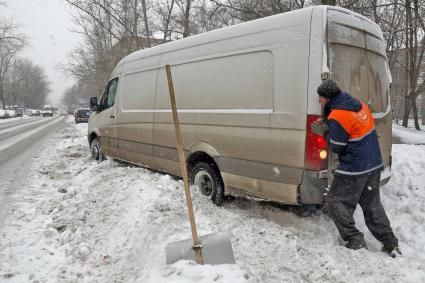 Снегопад в Москве. На снимке: дворник помогает водителю выехать из сугроба.