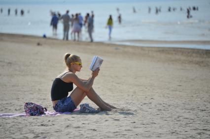 Отдых на море. На снимке: девушка на пляже читает книгу.