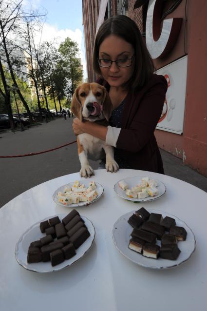 Женщина с собакой у стола с конфетами.