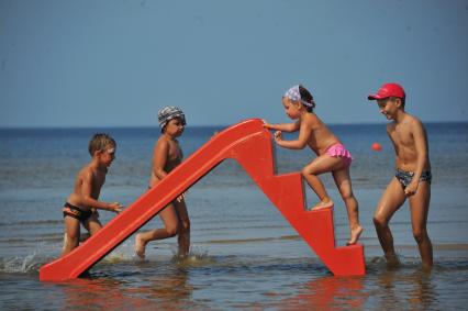 Отдых на море. На снимке: дети скатываются с горки в море.