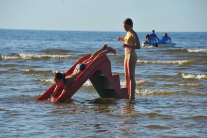 Отдых на море. На снимке: девочки скатываются с горки.