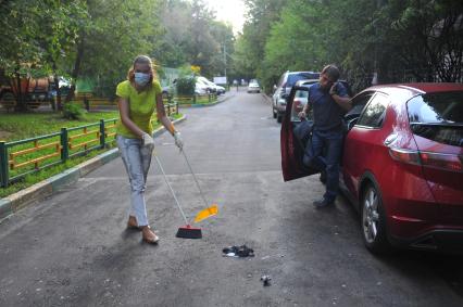 Девушка убирает мертвого голубя с асфальта.