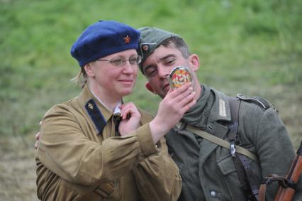 Военно-историческая реконструкция событий Второй мировой. На снимке: участники военной реконструкции, женщина в советской военной форме и мужчина в немецкой военной форме.