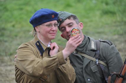 Военно-историческая реконструкция событий Второй мировой. На снимке:  участники военной реконструкции, женщина в советской военной форме и мужчина в немецкой военной форме.