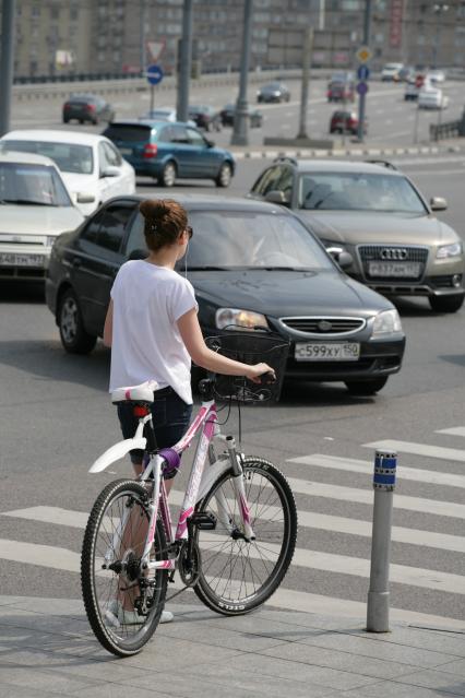 Девушка с велосипедом на пешеходном переходе.